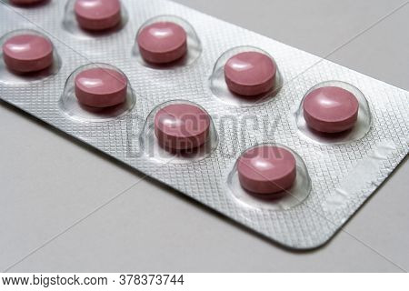 Pink Round Pills, One Packs Of Pills, Located On The Center Of The Image On A Gray Background Closeu