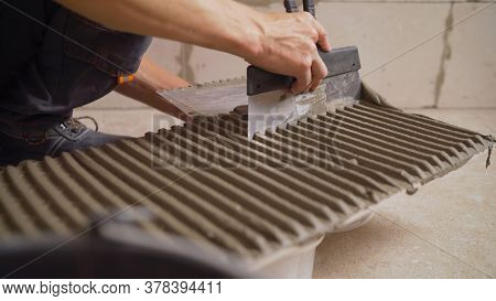 The Master Smears The Tiles With Glue. The Master Tile Smears The Mucilage Solution On The Marble Ti