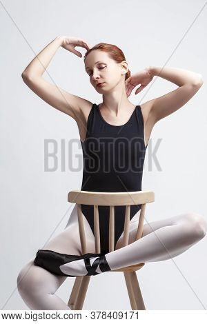 Ballet Concepts. Caucasian Female Ballet Dancer In Body Suit And Pointes Shoes Sitting On Chair With