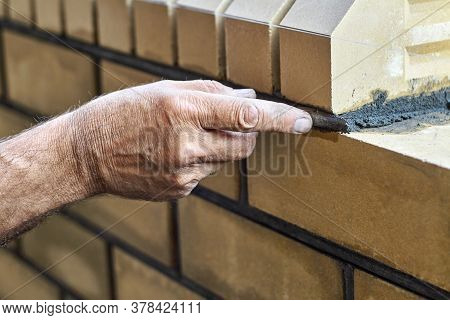 Bricklayer Builds New Fence From Facing Bricks. Alignment Of Inter-brick Joints