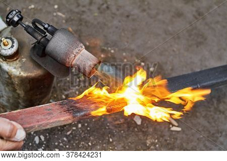 A Man Is Burning The Board Using The Old Rusty Blowtorch. Handmaking Manufacturing Process Of Burnt 