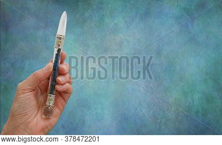 Cavansite Crystal Wand Message Banner - Female Hand Holding Wand Upwards Against A Blue Green Rustic