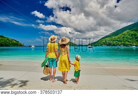 Family on beach, young couple in yellow with three year old boy. Summer vacation at Seychelles. Port Launay, Mahe. 