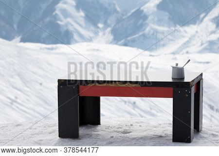 Old Table With Sugar Bowl In Outdoor Cafe At Ski Resort And Snowy Mountains At Background. Caucasus 