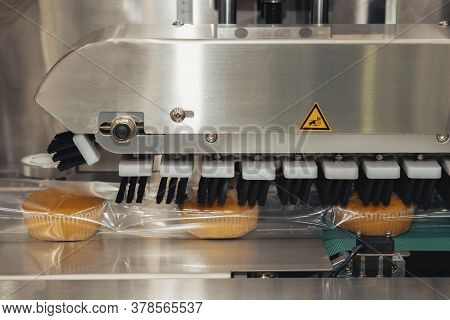 Baked Bread In Food Grade Plastic Bag On Conveyor Belt Moves To Seal In Packing Machine At Productio