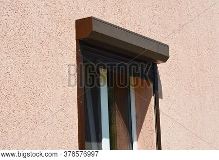 A Close-up On An Open Brown Exterior Pvc Motorized Window Roller Shutter On A Painted House.