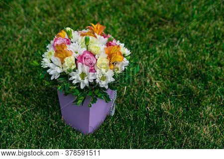 A Bouquet Of Colorful Flowers In A Hatbox On A Green Lawn. Top View. Place For Text.