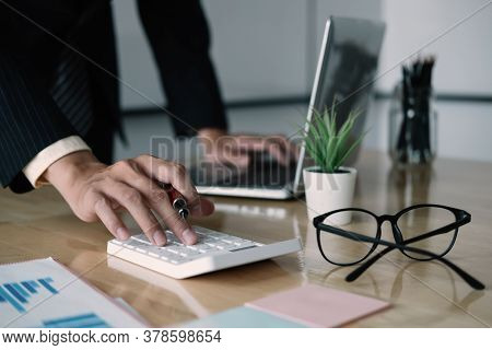 Close Up Of Businessman Or Accountant Hand Holding Pen Working On Calculator To Calculate Business D
