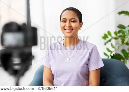 blogging, videoblog and people concept - happy smiling african american female video blogger with camera videoblogging at home