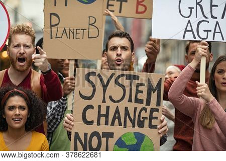 Group of multiethnic men and women protesting with placards. Group of demostrators with banners protest as part of a climate change. Protestors people holding signs and posters on global strike.