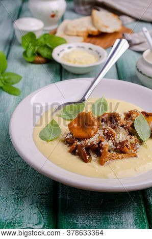 Traditional Polenta With Mushrooms And Cheese In A Dish On A Green Wooden Background. Selective Focu