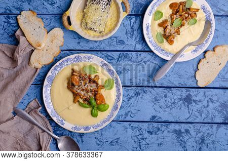 Traditional Polenta With Mushrooms And Cheese In A Dish On A Blue Wooden Background. Selective Focus