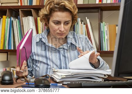 Image Of A Busy Woman Teleworking At Her Desk At The Home. Working At Home Became An Important Recom