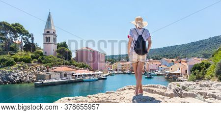 Woman Traveler Wearing Straw Summer Hat And Backpack, Standing At Edge Of The Rocky Cliff Enjoying B