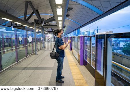 Nonthaburi Province, Thailand - 14 Jul 2020, Asian Man Is Standing And Playing His Mobile Phone Whil