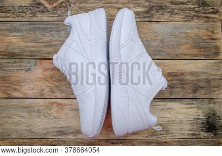 Beautiful Pair Of New White Women's Sneakers On A Wooden Background Close Up, View Top