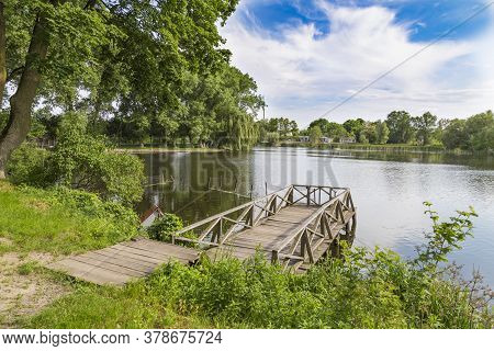 Summer Landscape On The Lake With A Wooden Bridge. Landscape Park In The Palace And Park Ensemble In