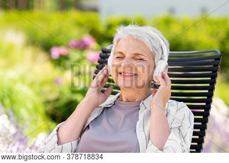 old age, retirement and people concept - happy senior woman with headphones listening to music at summer garden