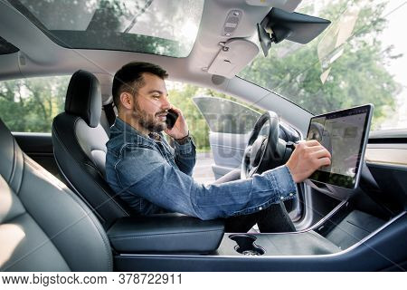 Testing A New Electric Futuristic Car With Self Driving System. Side View Of Satisfied Caucasian Man