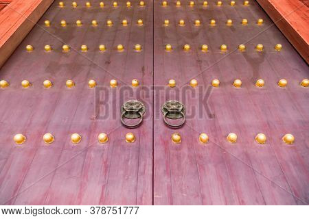 Red chinese wooden door with metal knocker and golden knocker nails in Beijing,China