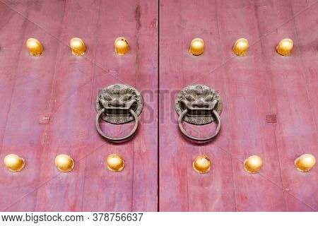 Red chinese wooden door with metal knocker and golden knocker nails in Beijing,China