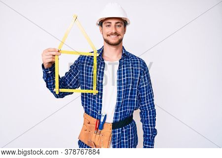 Young handsome man wearing architect hardhat holding build project looking positive and happy standing and smiling with a confident smile showing teeth 