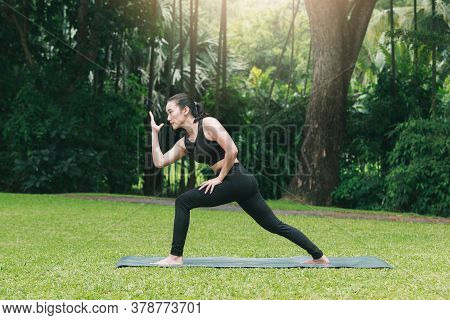 Asian Woman Practicing Yoga In Prep Poses For Side Crane Pose For Parsva Bakasana On The Mat In Outd