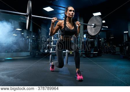 Side View Of Female Bodybuilder With Braids Doing Lunges Using Barbell. Srtong Brunette Woman With M