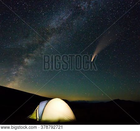 Tourist Hikers Tent In Mountains At Night With Stars And Neowise Comet With Light Tail In Dark Night