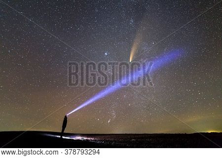 Silhouette Of A Man With Flashlight On His Head Pointing Bright Beam Of Light On Starry Sky With Neo