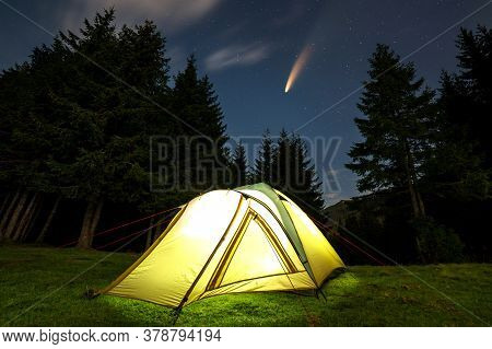 Illuminated Tourist Tent On Green Clearing With Distant Mountain And Starry Night Sky With C/2020 F3