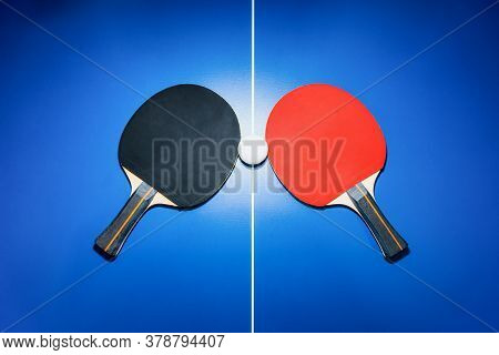 Top View Black And Red Table Tennis Racket And A White Ping Pong Ball On The Blue Ping Pong Table Wi