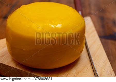 One Small Head Of Dutch Baby Gouda Cheese In Yellow Wax Close Up