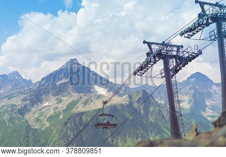 Cableway On Mountaintop In Cloudy Weather. Modern Ropeway With Benches In Amazing Mountainous Terrai