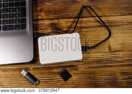 External Hdd Connected To Laptop Computer, Sd Memory Card And Usb Flash Drive On A Wooden Desk. Top 