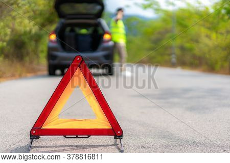 Breakdown Triangle Sign On Road With Worried Asian Man Talking By Mobile Phone With Insurance Or Car