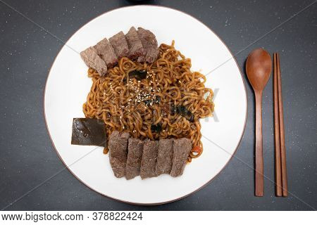 Top View Image Of Korean Black Bean Noodles, Jajjangmyeon With Wooden Spoon And Chopstick.
