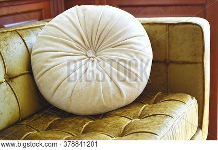Round Beige Pillow On Golden Velor Sofa