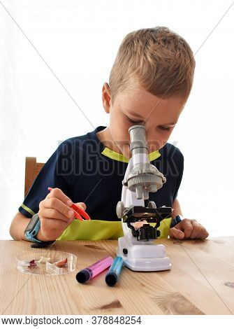 Boy Sitting And Looking Through A Microscope