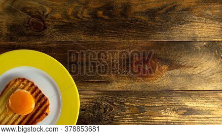 Sandwich With Fried Yolk And Toasted Bread On Plate With Yellow Edge On Rough Wooden Background Or T