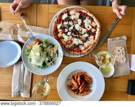 Italian Food Table With Penne Pasta,  Funghi Mushroom Pizza, Parmesan Cheese Salad And White Wine At