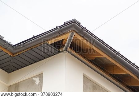 Close-up View Of Corner Of House With A Gray Roof And Plums And Filing Of Roof Overhangs With Soffit