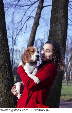 Pretty Young Girl In Redd Coat Playing With Dog Outside In Green Park, Lifestyle People Concept