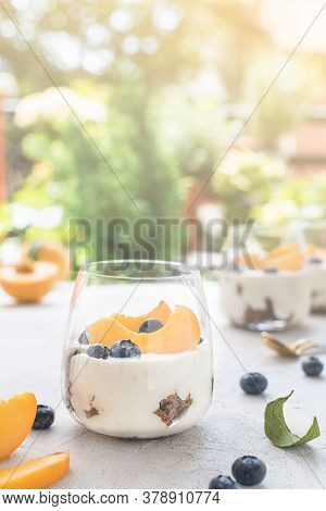 Individual Layered Desserts With Sponge Cake, Cream And Peach Fruit, Blueberry, Trifle