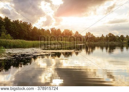 Summer Landscape: The Sky With Clouds And The Forest On The Horizon Are Reflected In The Clear Water