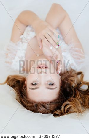 The View From The Top. Beautiful Bride In White Dress Lying In Bed. Close-up.