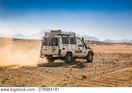 Hurghada, Egypt- Feb 4 , 2020:  Car or jeep offroad vehicle driving in desert sand dunes surface on blue sky background, safari and adventure, near Hurghada, Egypt.