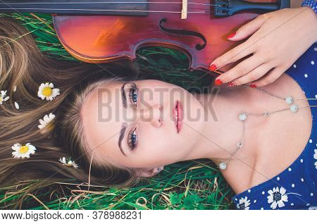Young Girl Blonde Lies In Grass With Violin.
