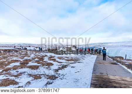 Gullfoss, Iceland - March 4, 2020: Tourists At Observation Deck Look At Gullfoss Waterfall. People A