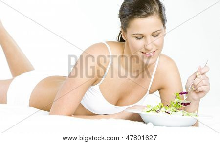 liggende kvinde spiser salat